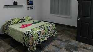 Een kamer met een bed, een plank met een radio, een raam met gordijnen en een deur.