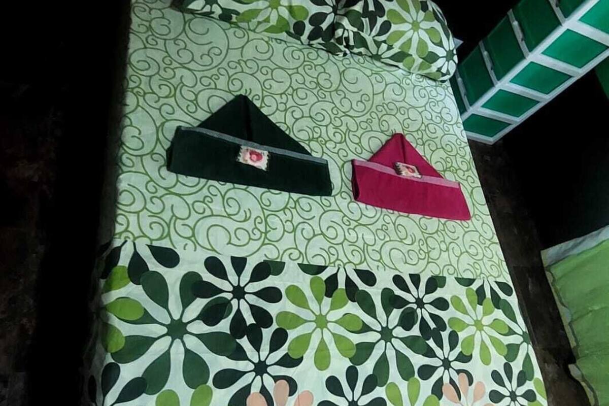 Un lit avec une couvre-lit à motifs, des oreillers et une table de chevet avec une lampe.