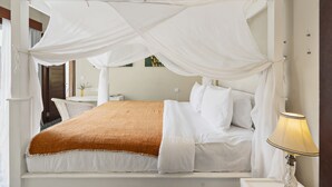 A bed with a white canopy, a bedside lamp, and a small table with a vase. - Bamboo Damai Villa by Betterplace (Kerobokan)
