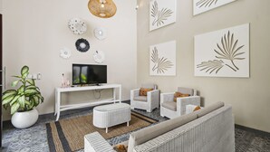 A living room with a TV, white furniture, decorative wall art, and a potted plant. - Bamboo Damai Villa by Betterplace (Kerobokan)