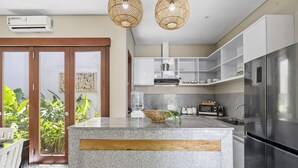 A modern kitchen with granite countertops, stainless steel appliances, and a large island. - Bamboo Damai Villa by Betterplace (Kerobokan)