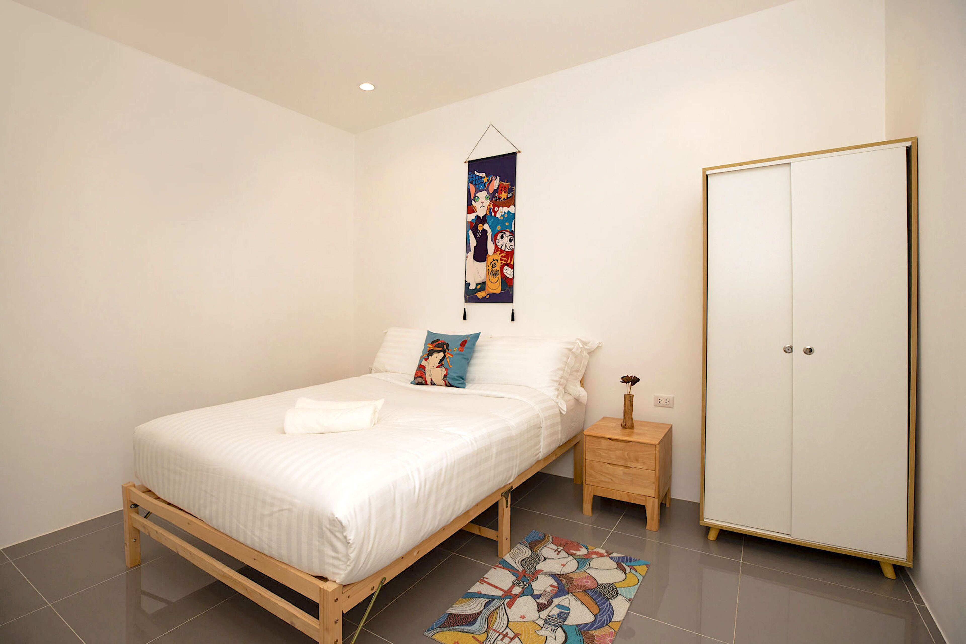 Une chambre à coucher avec un lit en bois, une table de chevet, une armoire et un tapis coloré.