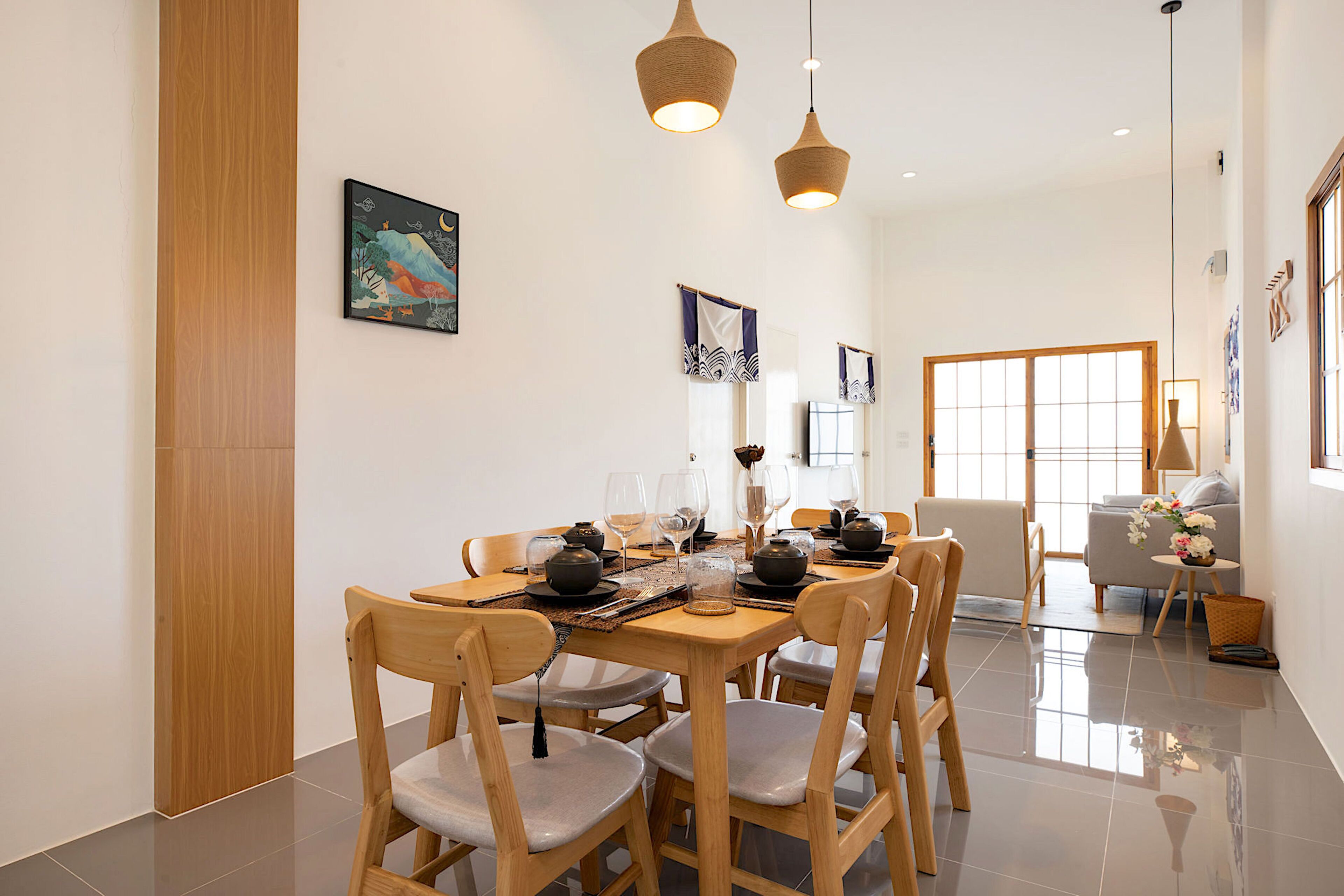 A dining area with a wooden table set for a meal, surrounded by chairs.