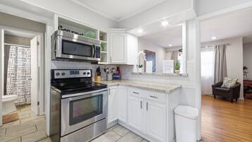 A modern kitchen with white cabinetry, stainless steel appliances, and a tiled backsplash.