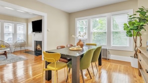Un coin repas avec une table en bois, des chaises et une cheminée.