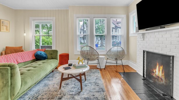 Un salon avec un canapé vert, une cheminée et un téléviseur.