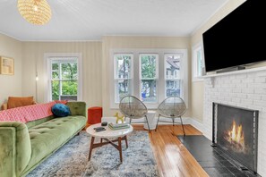 A living room with a green sofa, a fireplace, and a television.