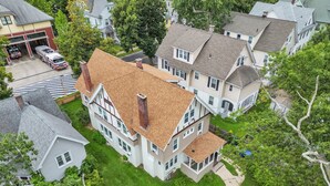 Une grande maison à deux étages, dotée d’une cheminée imposante, d’une pelouse bien entretenue et, au loin, d’une caserne de pompiers.