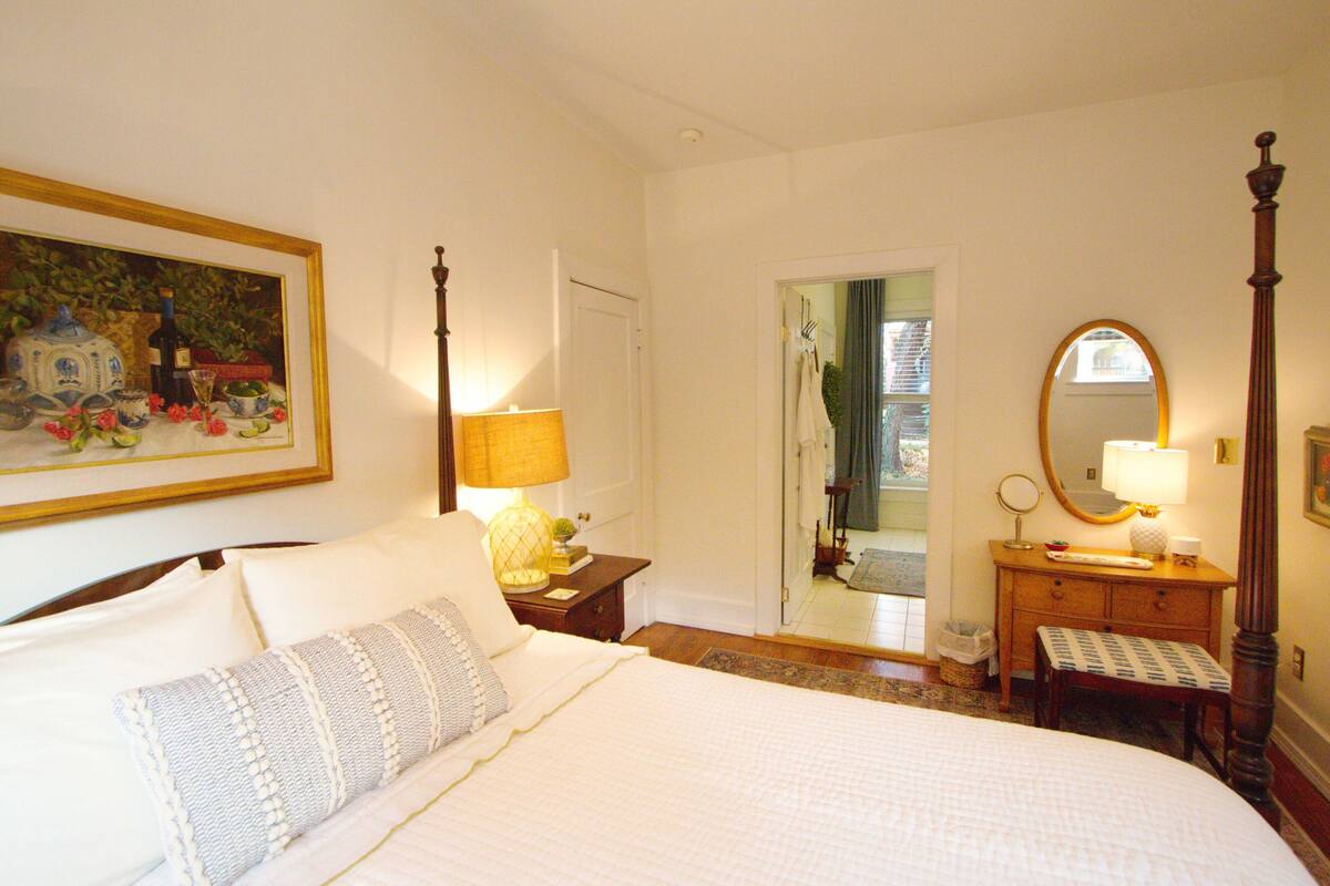 A bedroom with a bed, a nightstand, a dresser, a mirror, and a painting on the wall.