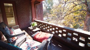 A covered outdoor seating area with wicker furniture and a wooden railing. - Louisville Bourbon Inn (Louisville)