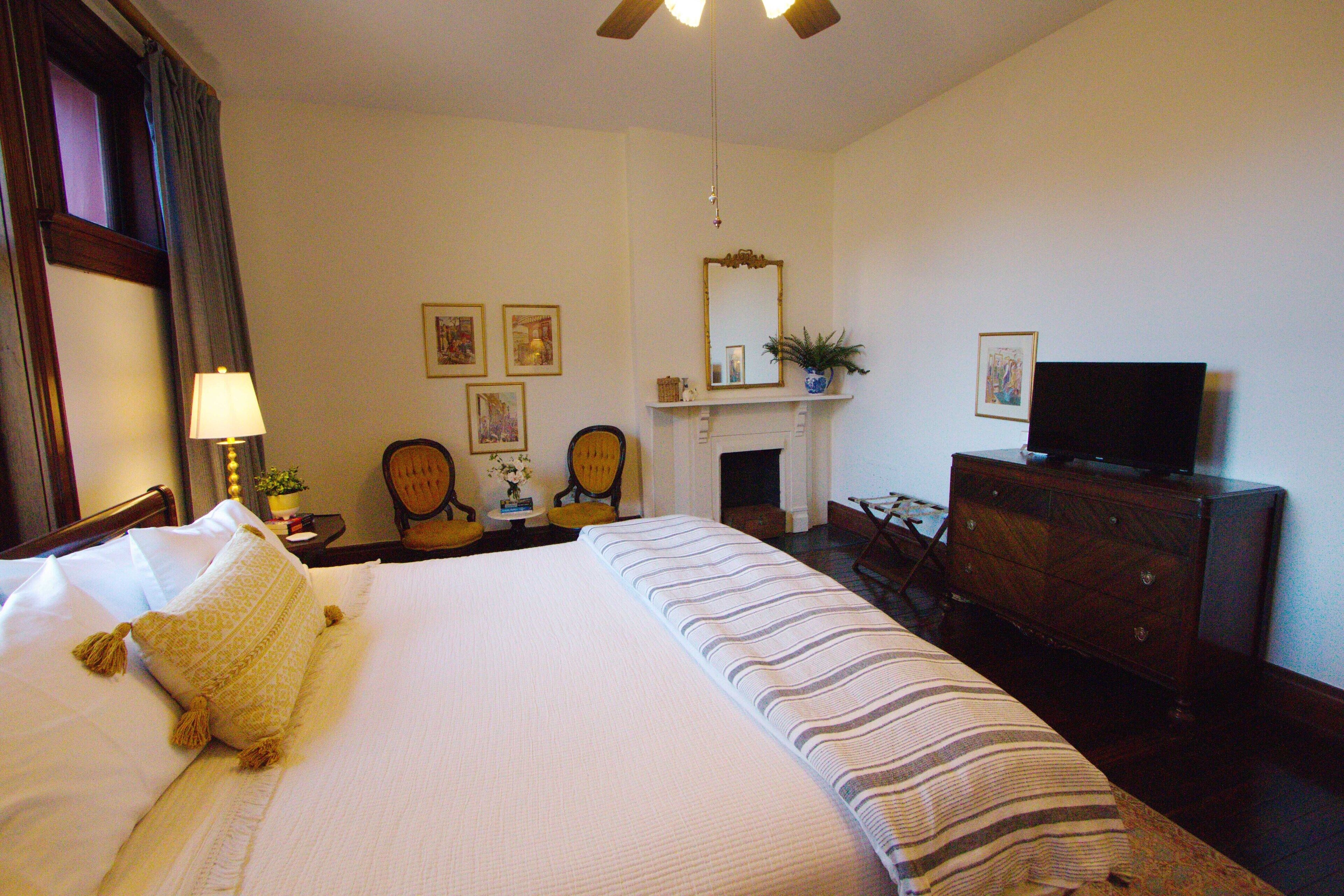 Habitación de hotel con una cama grande, televisión, cómoda y chimenea.