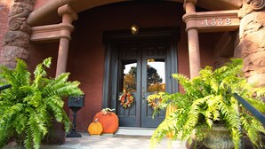 A building entrance with a dark door, a large number '1332' above it, and two large potted ferns on either side. - Louisville Bourbon Inn (Louisville)