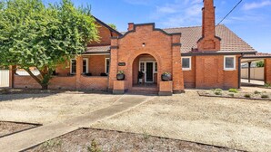 A brick building with a central archway, a chimney, and a sign reading "Rose's Rest".