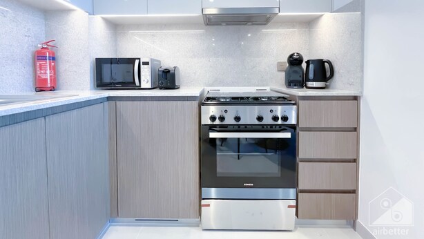 A modern kitchen with a stainless steel stove, a microwave, a toaster, and a coffee maker. - Luxury 2bed Balcony City View (Dubai)