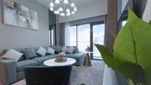 Una sala de estar moderna con un sofá gris, una mesa de centro redonda y una planta verde grande.