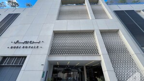 Un edificio moderno con fachada geométrica, una entrada destacada con puertas de vidrio y un letrero que indica el nombre 'Burj Royal'.