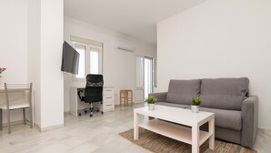 A modern living room with a grey sofa, a white coffee table, and a TV mounted on the wall.