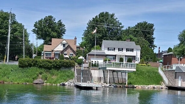 Ein Steg, der sich in ein ruhiges Gewässer erstreckt, mit einem Haus und einer Brücke in der Nähe.