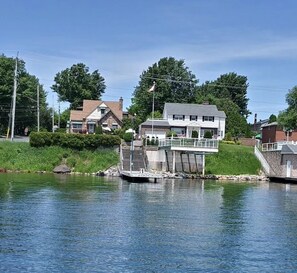 A dock extending into a calm body of water with a house and a bridge nearby. - Monte Carlo Motel (Cornwall)