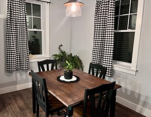 Enjoy meals in this cozy dining area with a wooden table and four chairs, surrounded by a potted plant and pendant light.