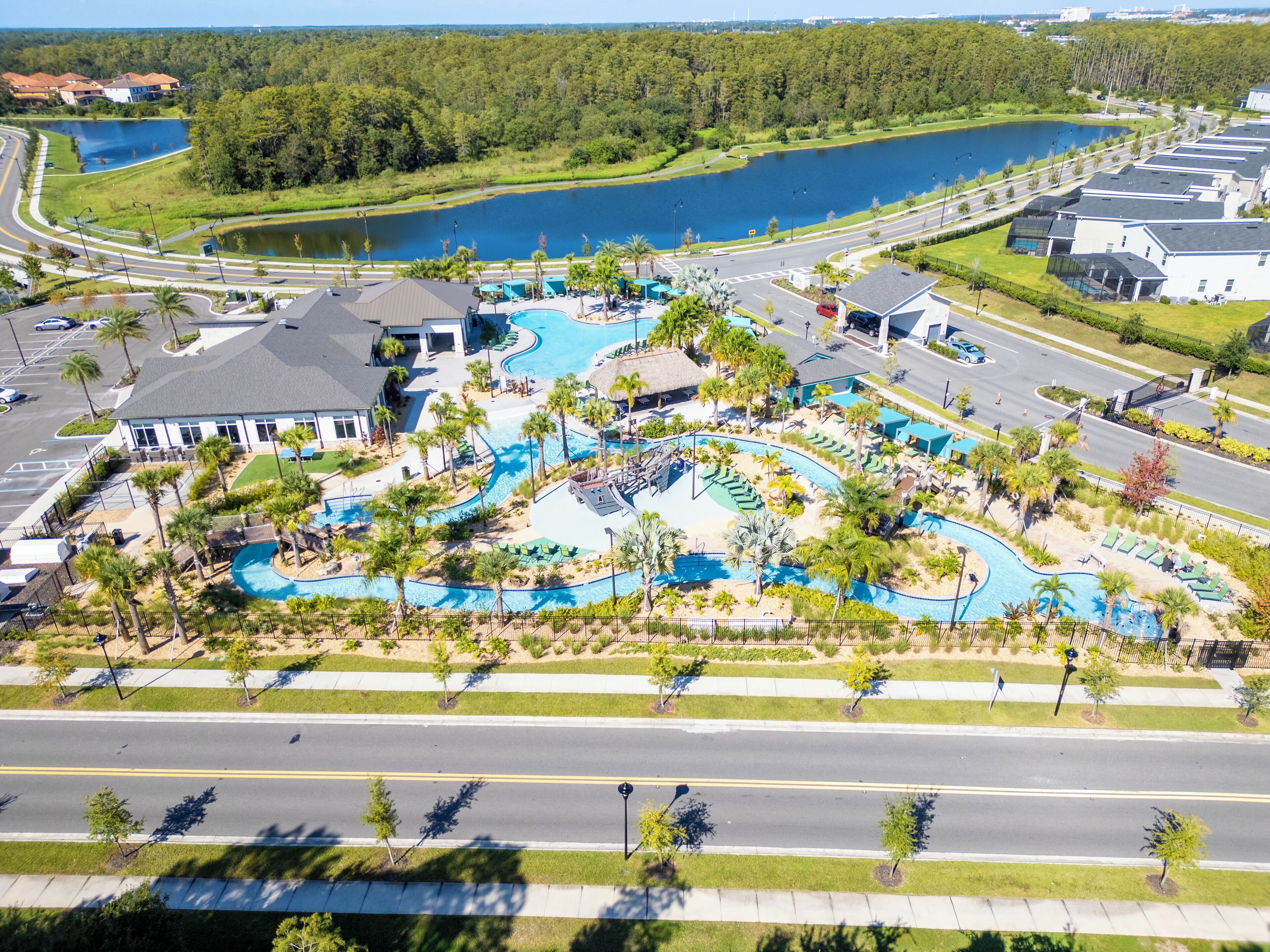 Eine Luftaufnahme eines Resorts mit mehreren Schwimmbecken, einem großen See und einer Straße mit Fußgängerweg.