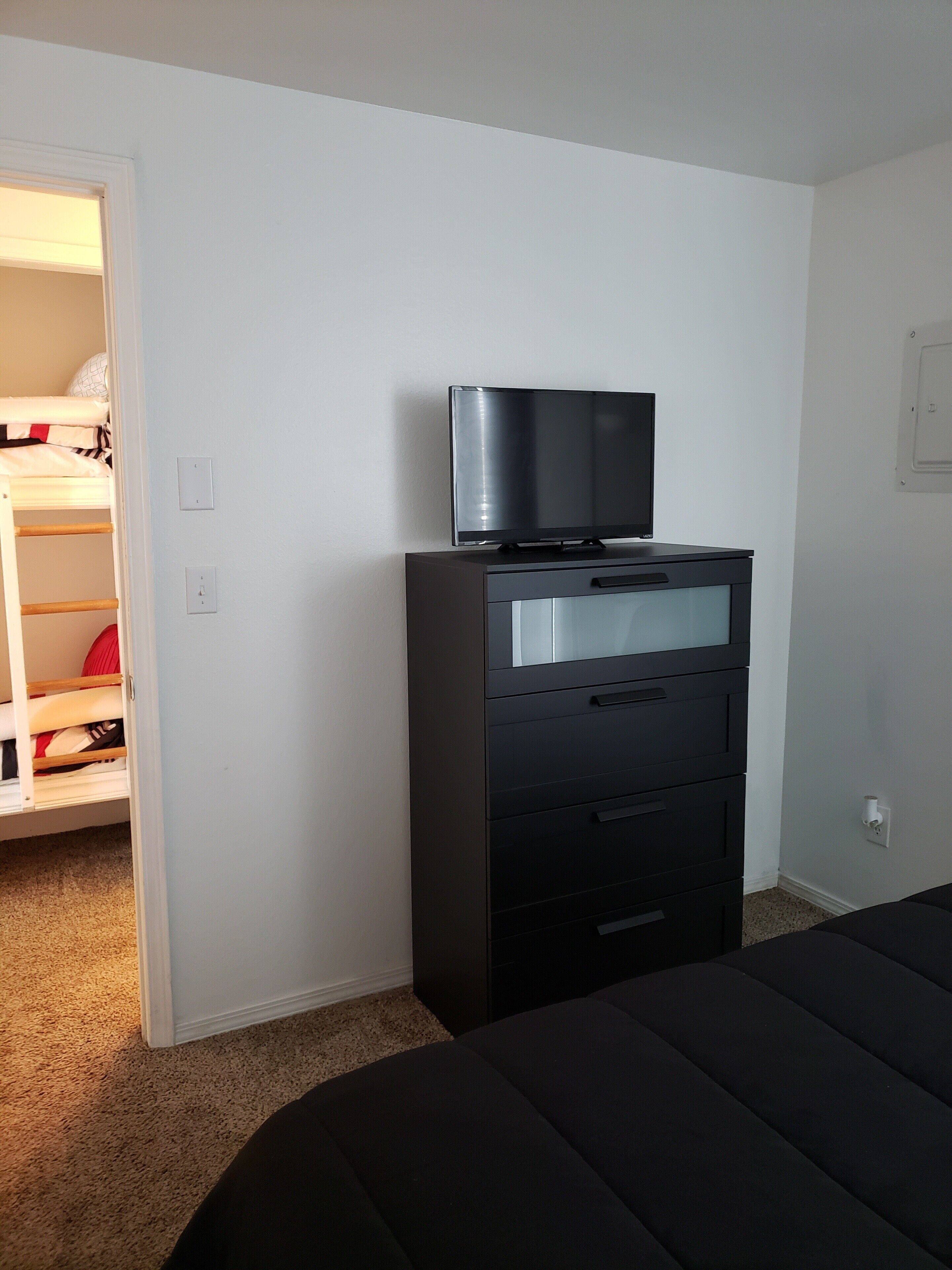 Een slaapkamer met een bed, een dressoir en een televisie erboven.