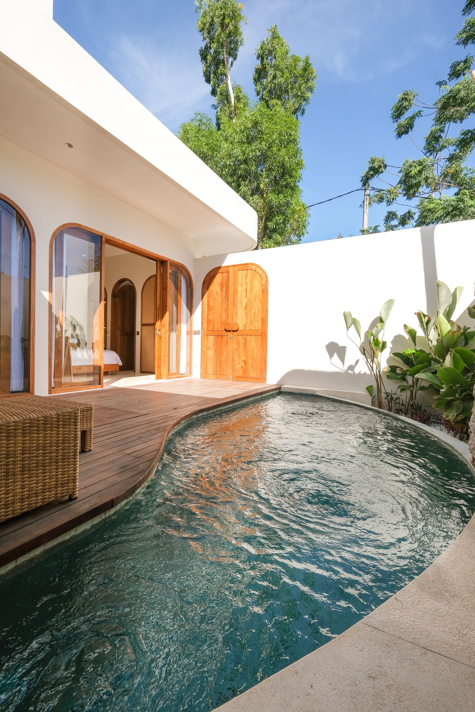 Una casa moderna con piscina, puertas de madera y un patio cubierto.