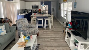 A modern living room with a sofa, a coffee table, and a TV stand. There is a kitchen area with a dining table and chairs. - Coconut In Paradise Key largo (Key Largo)