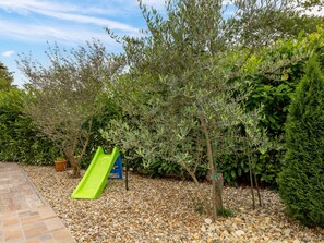 Enjoy a serene outdoor space surrounded by lush greenery and a fun green slide for kids.