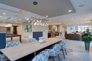 Relax in a spacious room with a dining table, sofa, and armchairs, plus a pool table and kitchen area.