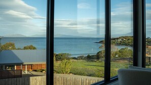 A modern house with large windows overlooking a coastal landscape.
