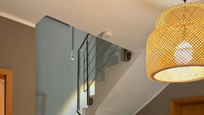 A staircase with a metal railing and a woven light fixture above.