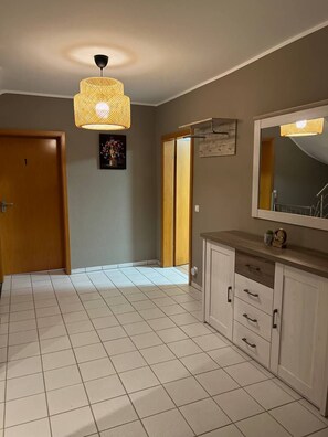 A bathroom with a large mirror, a cabinet with drawers, and a hanging light fixture. - Rheinview Urbar Haus (Urbar)