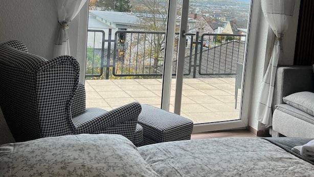 A balcony with a view of a cityscape, furnished with two sofas and a chair.