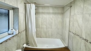 Ein kleines Badezimmer mit Fliesen, einer Duschvorhang, einer Toilette und einem Fenster.