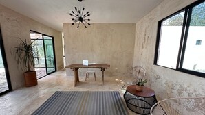A modern interior with a wooden dining table, a potted plant, a woven chair, and a unique ceiling light fixture. - xbalche eco hotel & RV park (Acanceh)
