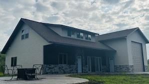 A modern two-story house with a stone foundation, a garage, and a patio with outdoor furniture. - Located in the Heart of MN Lakes Country with much to do in the area. (Lake Park)
