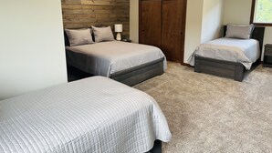 A bedroom with two beds, wooden ceiling beams, a wooden door, and a window. - Located in the Heart of MN Lakes Country with much to do in the area. (Lake Park)