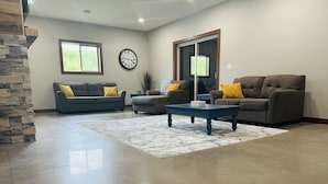 A spacious living room with two sofas, a coffee table, and a stone accent wall. - Located in the Heart of MN Lakes Country with much to do in the area. (Lake Park)