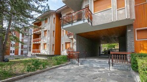 A multi-story residential building with balconies, a stone courtyard, and a staircase leading to the entrance. - The Secret Garden in the City center, Bardonecchia, Italy (Bardonecchia)