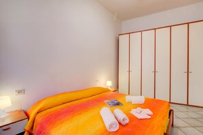 Une chambre d’hôtel comprenant un lit, une table de chevet, une lampe, une armoire et des serviettes.