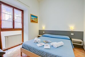 Une chambre d’hôtel avec un lit, un radiateur, un tableau et deux lampes de chevet.