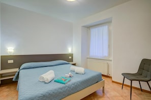 Une chambre à coucher avec un lit, des oreillers, une chaise et une fenêtre.