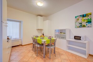 Un coin repas avec une table dressée pour quatre personnes, un four à micro-ondes et une étagère.
