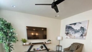 A modern living room with a sofa, armchair, coffee table, and a ceiling fan.