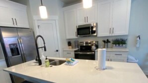 A modern kitchen with white cabinets, stainless steel appliances, and a large island with bar stools.