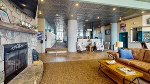 A spacious lobby with a stone fireplace, a wooden coffee table, and a leather sofa. - 8th-floor condo with mountain view, pools, hot tubs, saunas, & gym (Sugar Mountain)