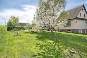 A residential area with a house, a lawn, a picnic table, and a tree.