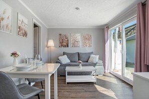 A modern living room with a sofa, dining table, and artwork on the walls.