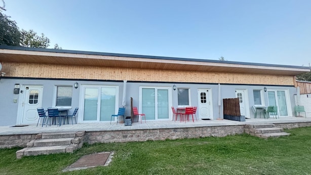 Un edificio moderno con techo plano, ventanas grandes y un patio cubierto con mobiliario exterior.